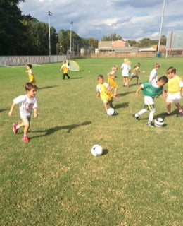 Kids playing soccer outdoors at camp