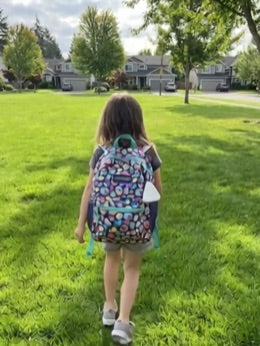 Pulse clipped to a child's backpack walking outside